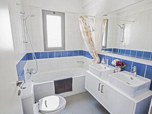 Ein modernes Badezimmer mit einer Badewanne, zwei Waschbecken, einer Toilette und einem Fenster.
