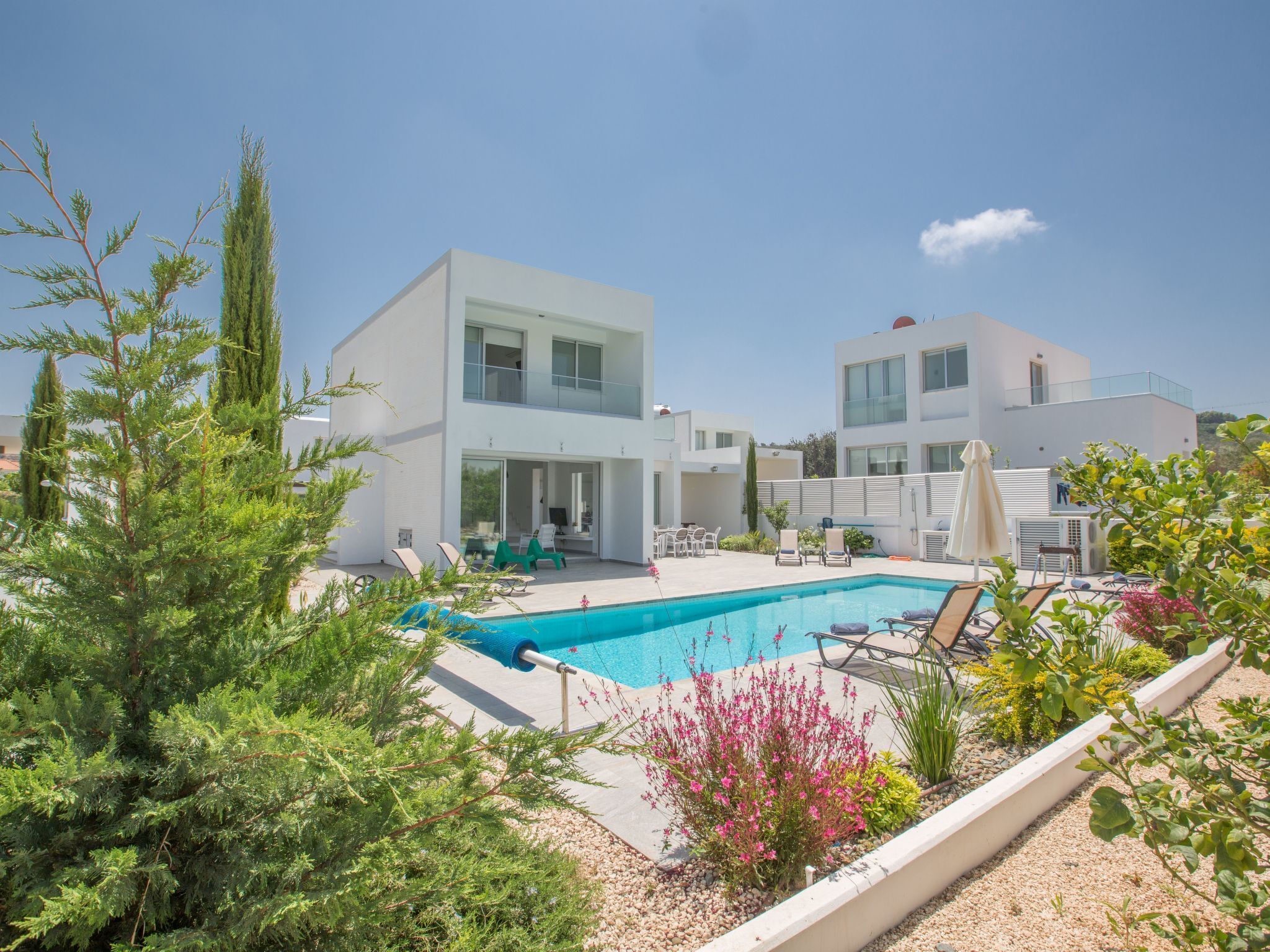 Ein modernes, zweistöckiges Gebäude mit Swimmingpool, Außenbereich und viel Grün.