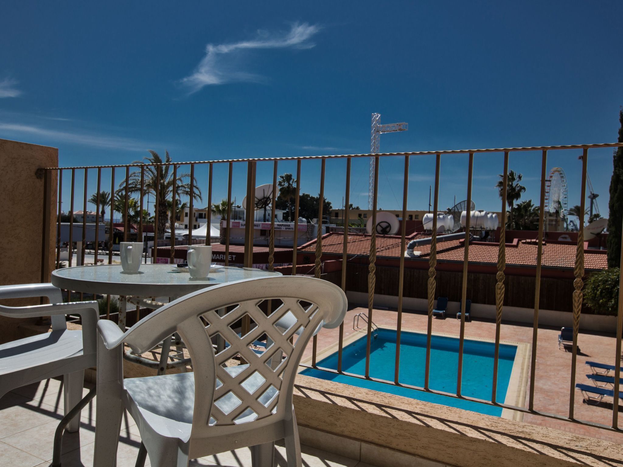 Area piscina con vista su una ruota panoramica e palme.