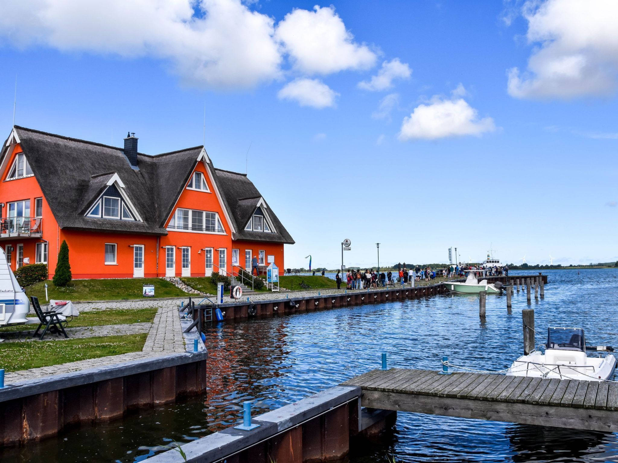 A red building with a black roof near a dock with boats.