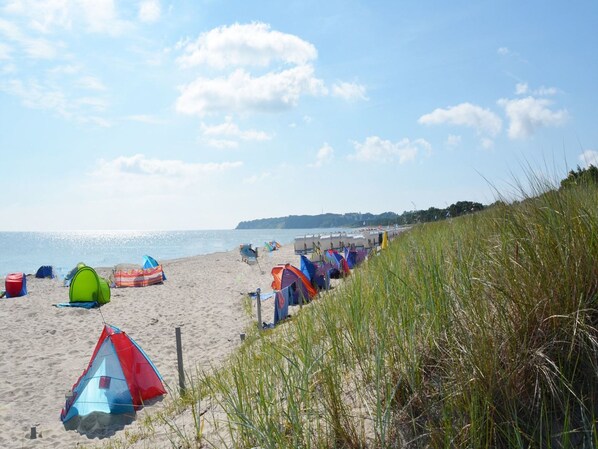Een strand met meerdere kleurrijke tenten en een gazon.