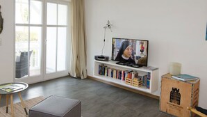 A living room with a television, bookshelves, a coffee table, and a sofa. - Appartement Sieben in Ostseebad Binz by Interhome (Binz)
