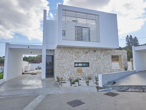 Ein modernes, zweistöckiges Haus mit Natursteinfassade, flachem Dach und minimalistischem Design.