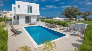 A modern two-story building with a swimming pool, outdoor seating, and a view of the sea. - Schöne, topmoderne Ferienvilla auf Zypern by Interhome (Paralimni)