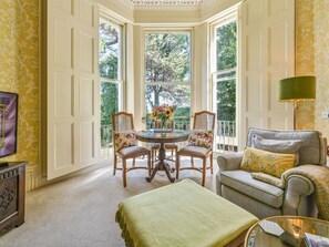 A room with a bay window, a round table with chairs, a sofa, and a lamp. - Luxuriöse Erdgeschosswohnung by Interhome (Torquay)