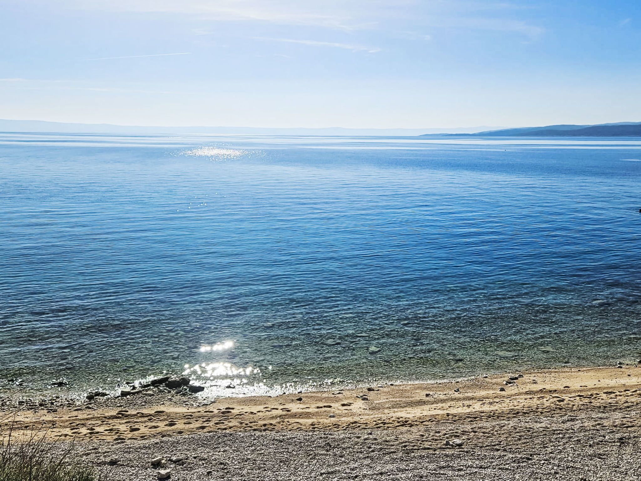 Ein Strand mit klarem Wasser und Kiesküste.