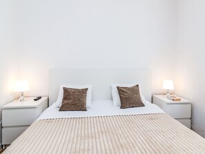 Een hotelkamer met een bed, twee nachtkastjes en twee lampen.