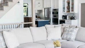 A modern living room with a large sectional sofa, a round wooden coffee table, and a staircase leading to an upper level. - Experience Ultimate Luxury at our Exquisite Lakehouse. Large family gatherings! (Erinsville)