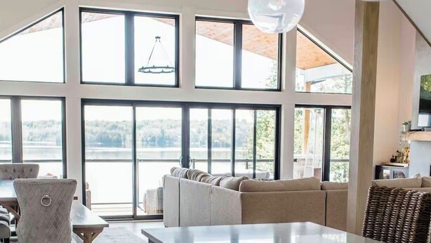 A spacious kitchen with a large island, dark cabinetry, and a view of a lake through large windows. - Experience Ultimate Luxury at our Exquisite Lakehouse. Large family gatherings! (Erinsville)