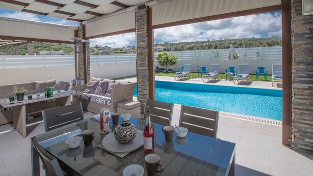 An outdoor pool area with lounge chairs and a table set for dining. - Moderne 4-Schlafzimmer-Villa im Zentrum von Protaras by Interhome (Protaras)