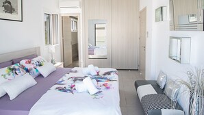 A modern hotel room with a large bed, a sofa, a mirror, and a wardrobe. - Moderne 4-Schlafzimmer-Villa im Zentrum von Protaras by Interhome (Protaras)