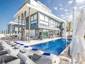 A modern two-story hotel with a large outdoor swimming pool, lounge chairs, and a covered seating area. - Haus in Paralimni mit großem Patio by Interhome (Paralimni)
