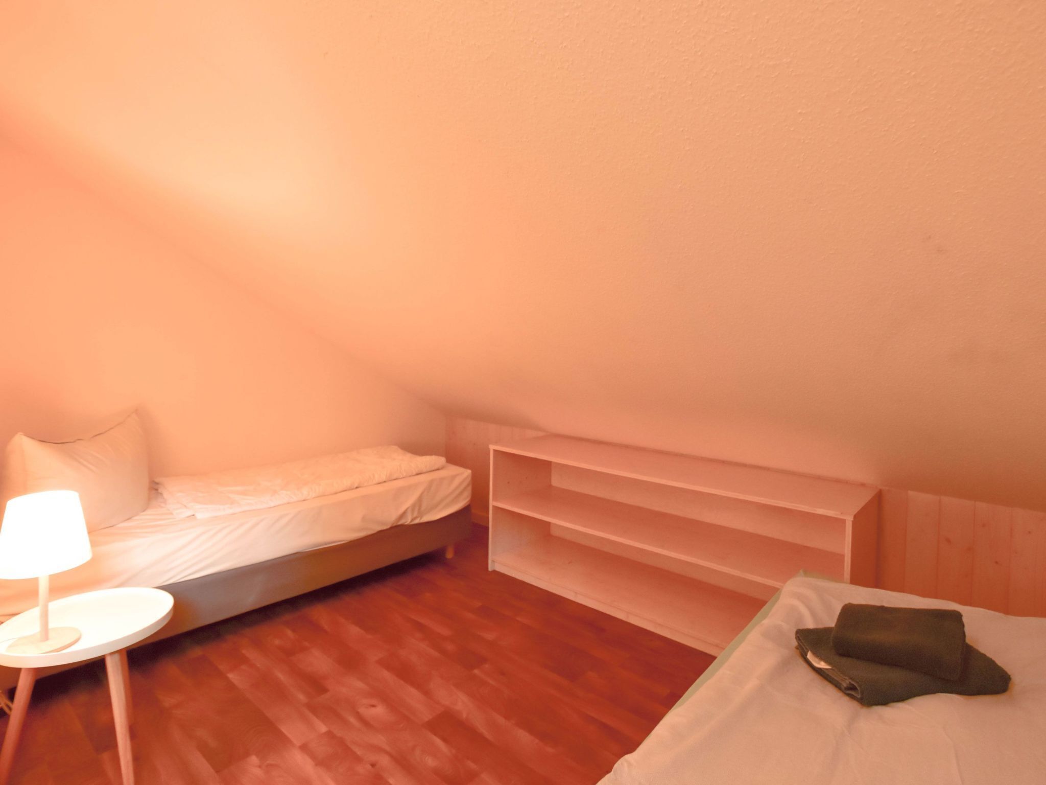 Una habitación pequeña y acogedora con una cama individual, una mesita de noche con lámpara y un estante empotrado.