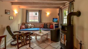 Una sala de estar acogedora con un sofá, sillas, una mesa de centro y un televisor.