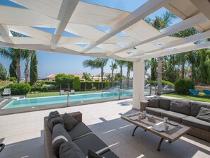 Ett takförsett utomhusområde med en pool, solstolar och en soffa.