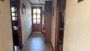 A hallway with tiled flooring, wooden doors, and a view into a room with a window. - Charming 4-bedroom house perfect for your getaway. Panoramic view from balcony (Guadalupe)