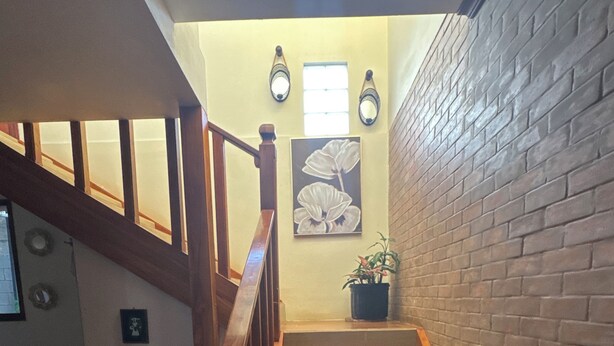 A staircase with wooden railings leading to a landing with a potted plant and a framed picture. - Charming 4-bedroom house perfect for your getaway. Panoramic view from balcony (Guadalupe)