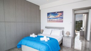 A modern bedroom with a large bed, grey wardrobe, and a painting of a beach scene. - Protaras Villa mit privatem Pool und Dachgarten by Interhome (Protaras)
