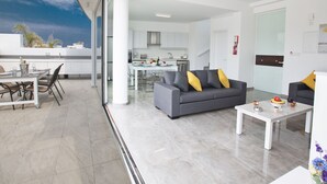 A modern apartment with a dining area, a gray sofa with yellow cushions, and a kitchen in the background. - Protaras Villa mit privatem Pool und Dachgarten by Interhome (Protaras)