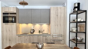 Eine moderne Küche mit Holztisch, integrierten Geräten und einer Kaffeemaschine.