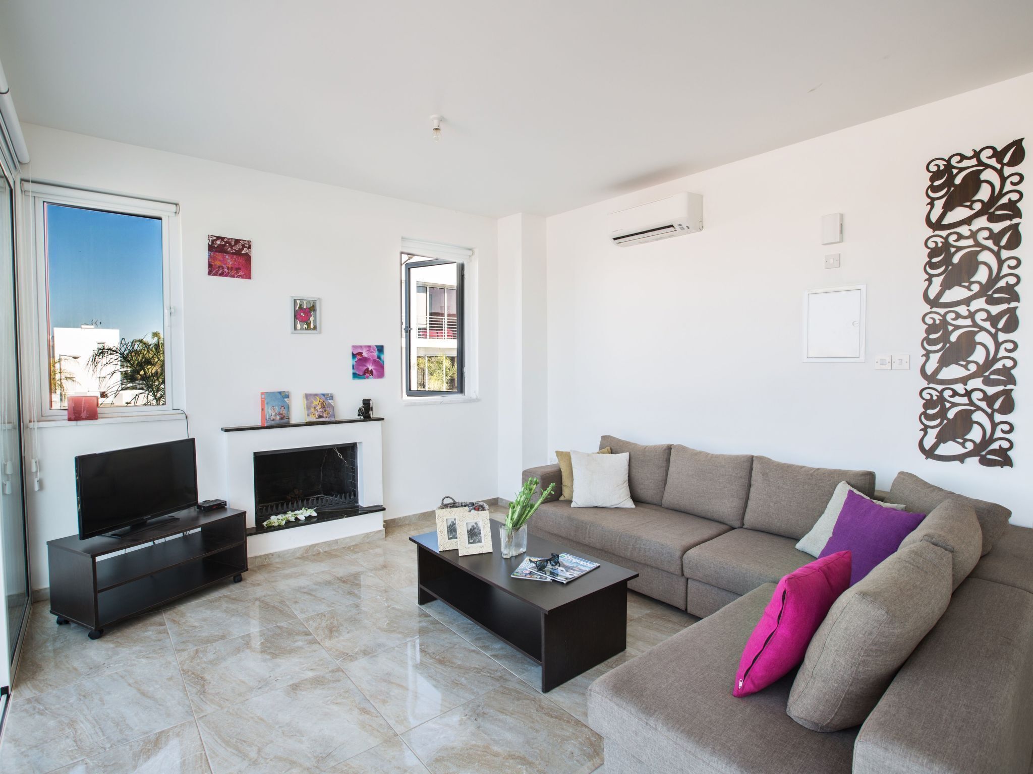 A modern living room with a flat-screen TV, a fireplace, a sofa, and a coffee table.