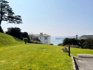 Une maison avec une pelouse et vue sur la mer.
