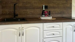 Cucina con pensili bianchi, zoccolo in legno, rubinetto nero e macchina da caffè sul piano di lavoro.