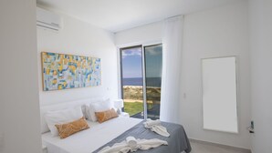 Un hotel moderno con una cama grande, vista a la playa y un cuadro en la pared.