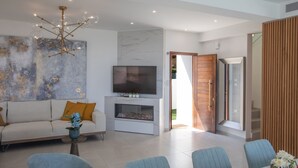 Una sala moderna con un sofá, una televisión y un comedor con sillas y una mesa.
