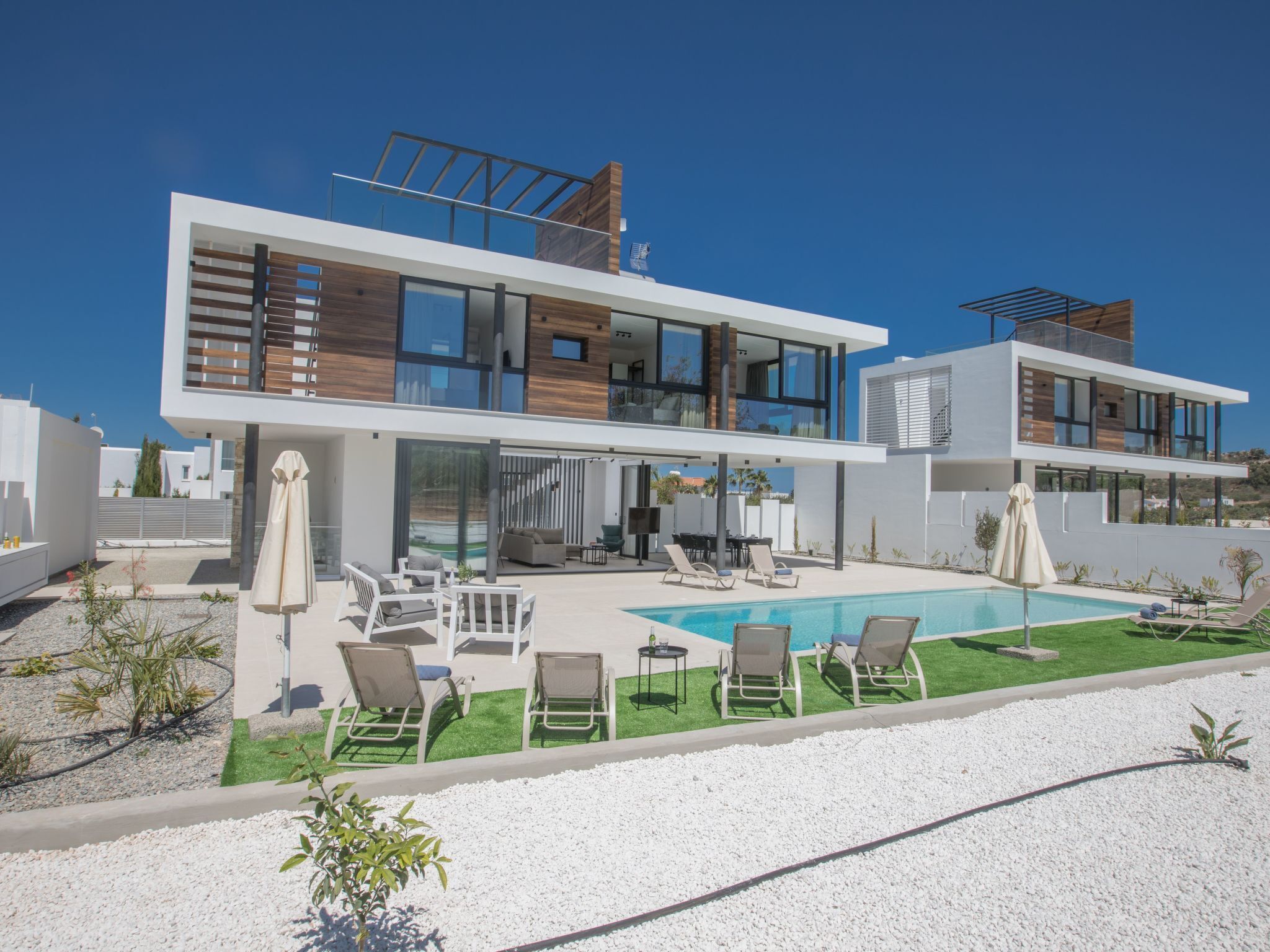 Ein modernes, zweistöckiges Haus mit Swimmingpool, Außenbereich und Blick auf die Umgebung.