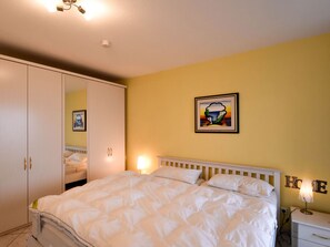 Ein Schlafzimmer mit Bett, Kleiderschrank, Nachttisch und Wandlampe.