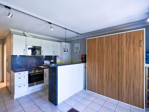 Eine moderne Küche mit weißen Schränken, einer zentralen Kochinsel und einem Holzschrank.