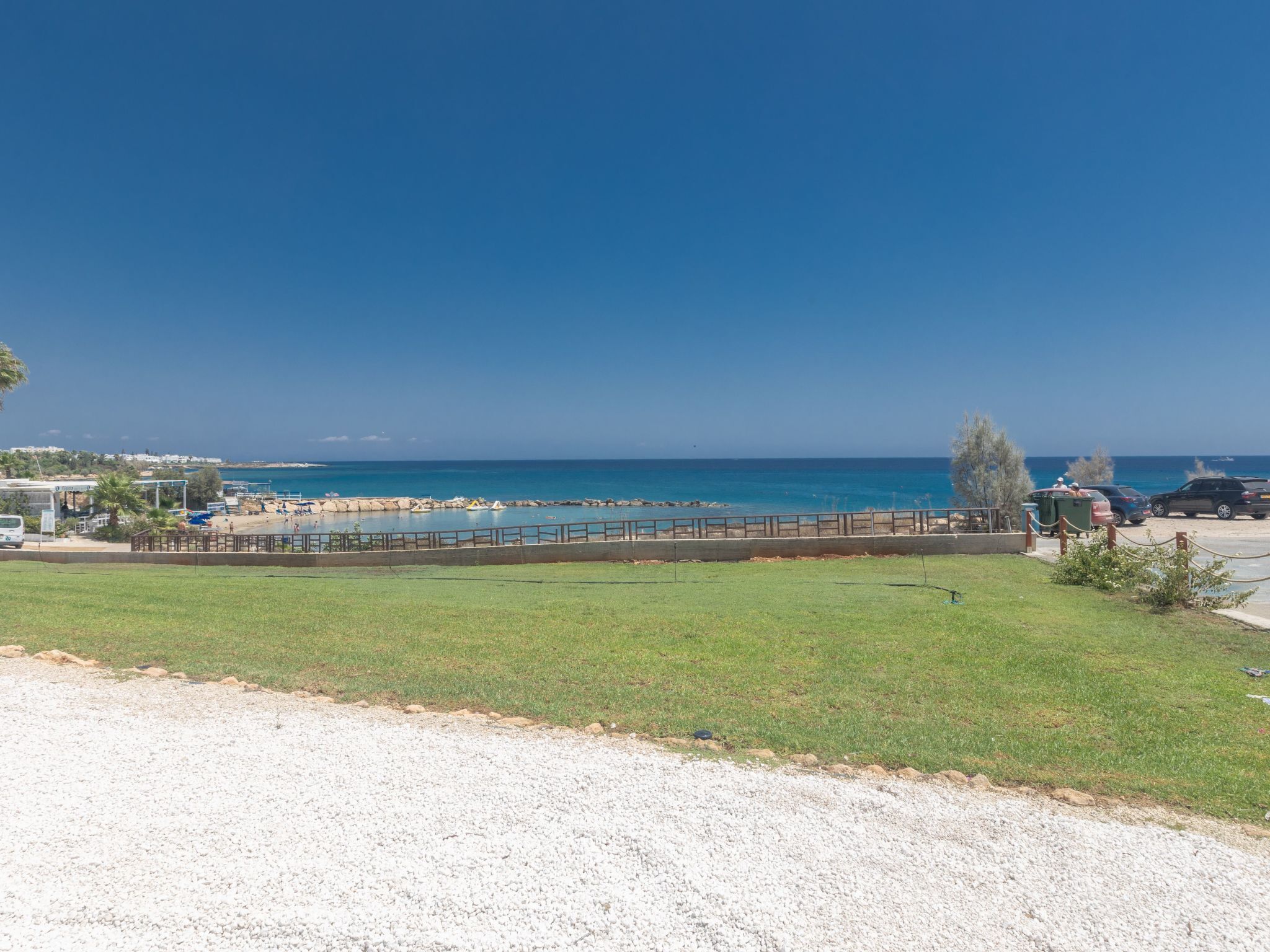 Blick auf die Küste mit Strand, Parkplatz und einer Wiese.