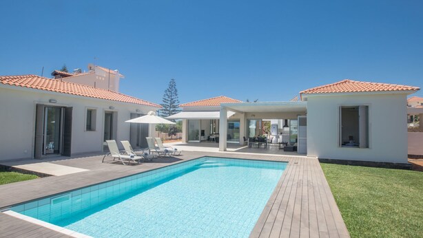 A modern pool area with a rectangular pool, lounge chairs, and a covered seating area. - in Ayia Napa mit großem Patio by Interhome (Ayia Napa)