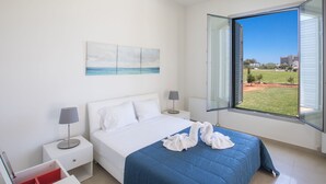 A bedroom with a bed, a nightstand, a lamp, a window with a view of the outdoors, and a painting on the wall. - in Ayia Napa mit großem Patio by Interhome (Ayia Napa)