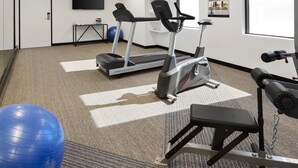 Un gimnasio con cintas de correr, una elíptica, una banca y una pelota de ejercicios azul.