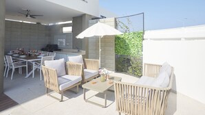 Un patio al aire libre con una mesa de comedor, sillas y zona de barbacoa.