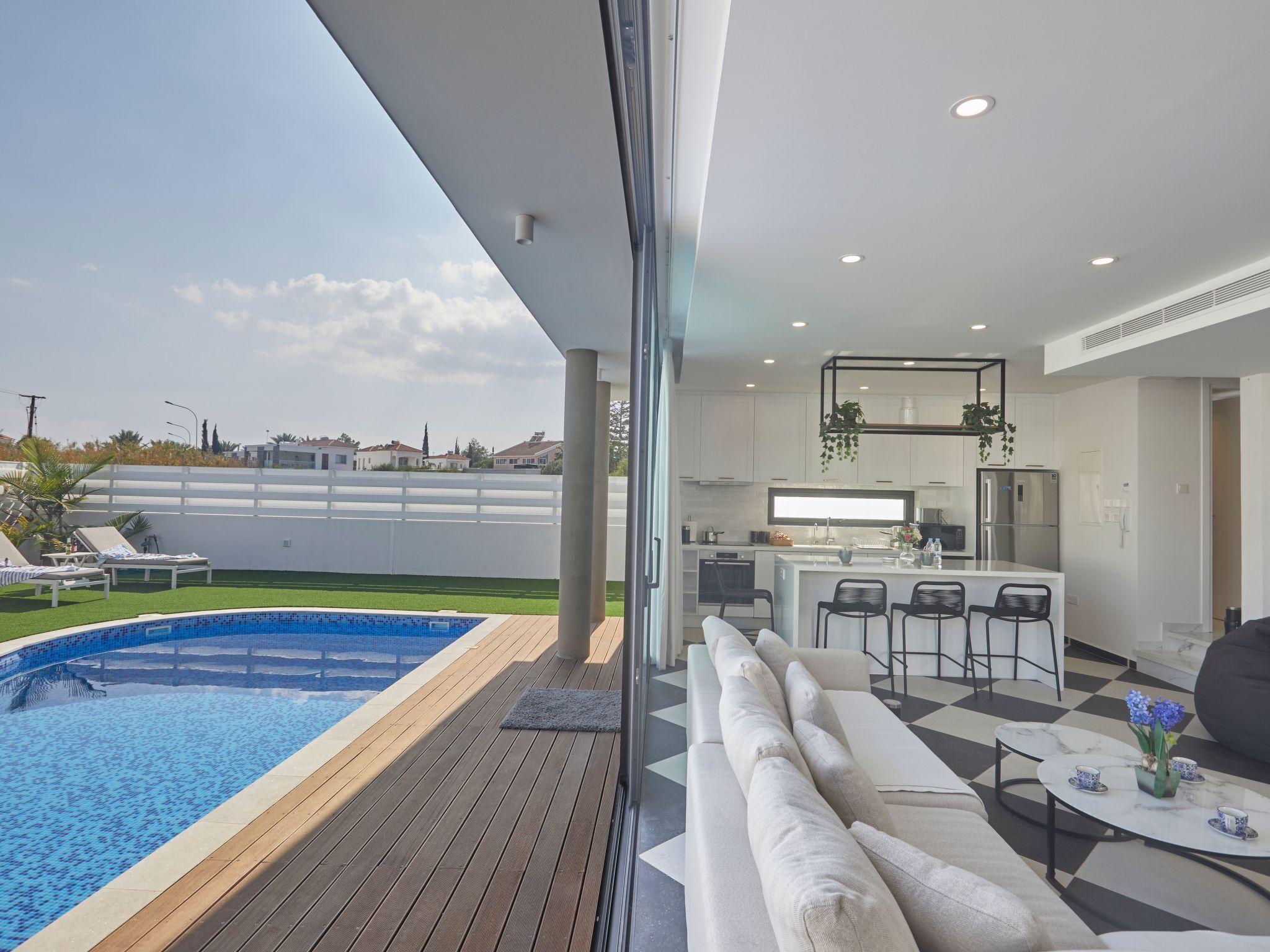 Una vivienda moderna con piscina, cocina y sala de estar con sofá y mesa de centro.