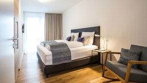 A modern hotel room with a large bed, bedside tables, a sofa, and a view of the outdoors. - Pfänder by Interhome (Friedrichshafen)