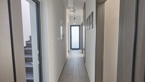 En modern hall med en trappa på vänster sida, en dörr på höger sida och en utsikt in i ett annat rum längst bort.