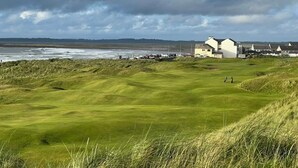 Rannikolla sijaitseva golfkenttä, jossa on klubitalo ja taustalla asuinrakennuksia.