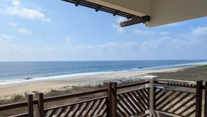 Een houten terras met uitzicht op het strand en de oceaan.