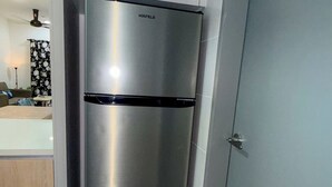 Uma cozinha moderna com frigorífico de aço inoxidável, porta cinzenta e chão em mosaico.