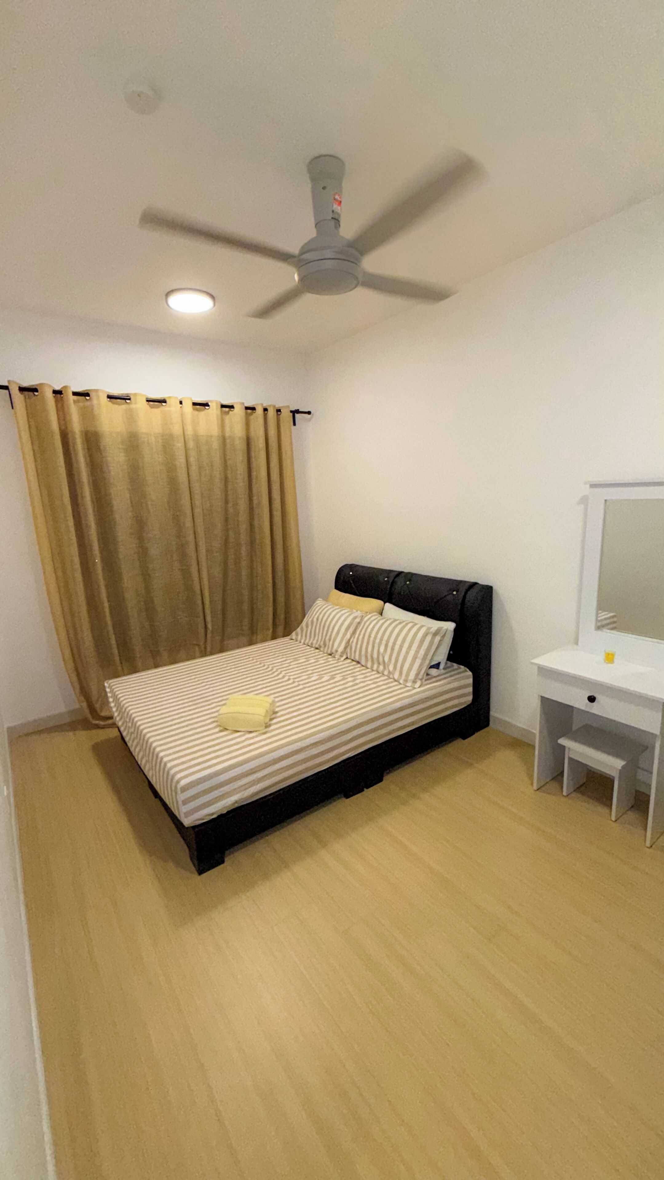 A bedroom with a bed, a ceiling fan, a bedside table, and a mirror.