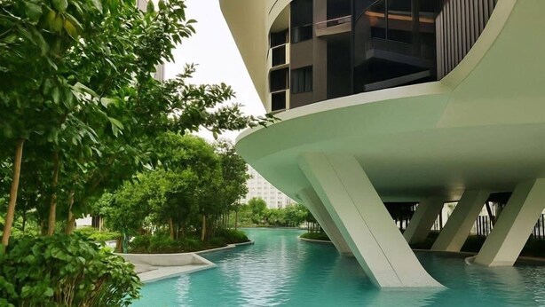 Um edifício moderno com design arquitetônico único, apresentando área de piscina rodeada por vegetação exuberante.