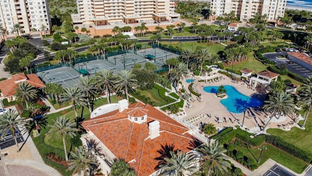 An aerial view of a hotel complex with multiple buildings, a central courtyard with a swimming pool, and surrounding greenery. - New Smyrna Beachfront Modern 9th Floor Condo Pool Hot Tub (New Smyrna Beach)