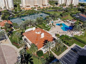 Oversigtsbillede af et hotelkompleks med flere bygninger, en central gårdsplads med swimmingpool og grøn beplantning omkring.