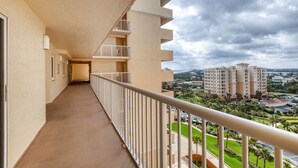 A long, narrow balcony with a metal railing, leading to a door at the end. - New Smyrna Beachfront Modern 9th Floor Condo Pool Hot Tub (New Smyrna Beach)