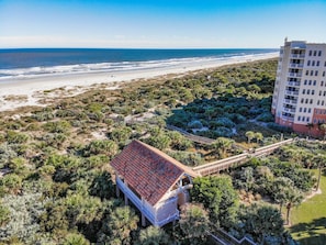 A coastal hotel with a beach view, a red-roofed building, and a multi-story structure in the background. - New Smyrna Luxury Beachfront Condo Pool Hot Tub (New Smyrna Beach)