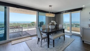 Un espace repas comprenant une table, des chaises et une vue sur l’océan.